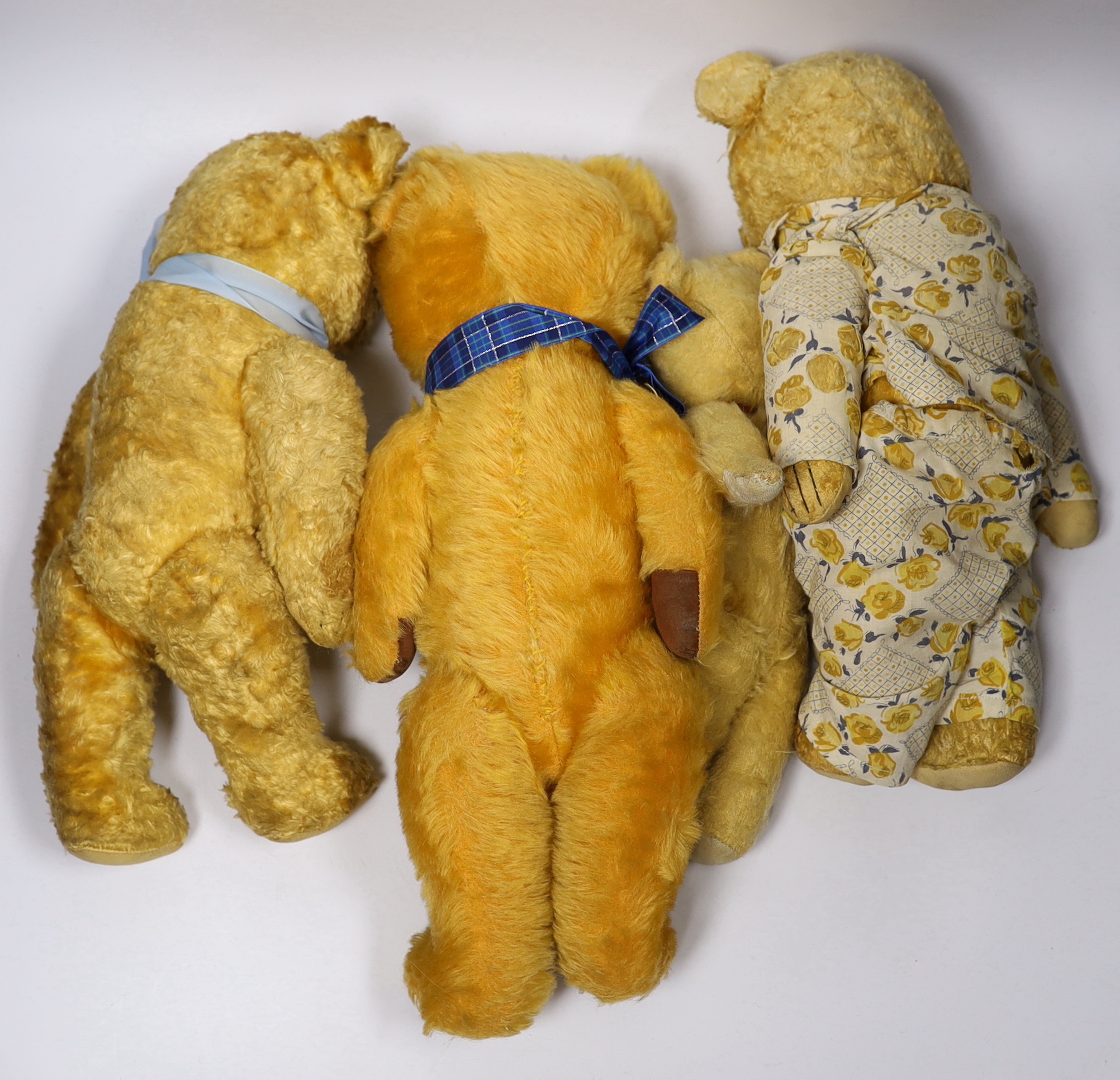 A golden plush bear with pale blue ribbon, 38cm, together with three others (4)